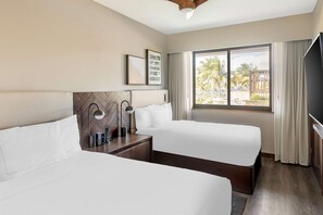 A hotel room with two beds, a large window with a view of palm trees, and a flat-screen TV.