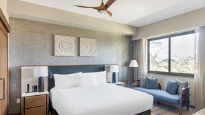 A modern hotel room with a large bed, bedside tables, a sofa, and a ceiling fan.