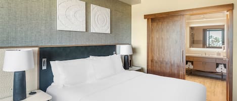 Een hotelkamer met een groot bed, twee nachtkastjes met lampen, een houten garderobe en een spiegel.