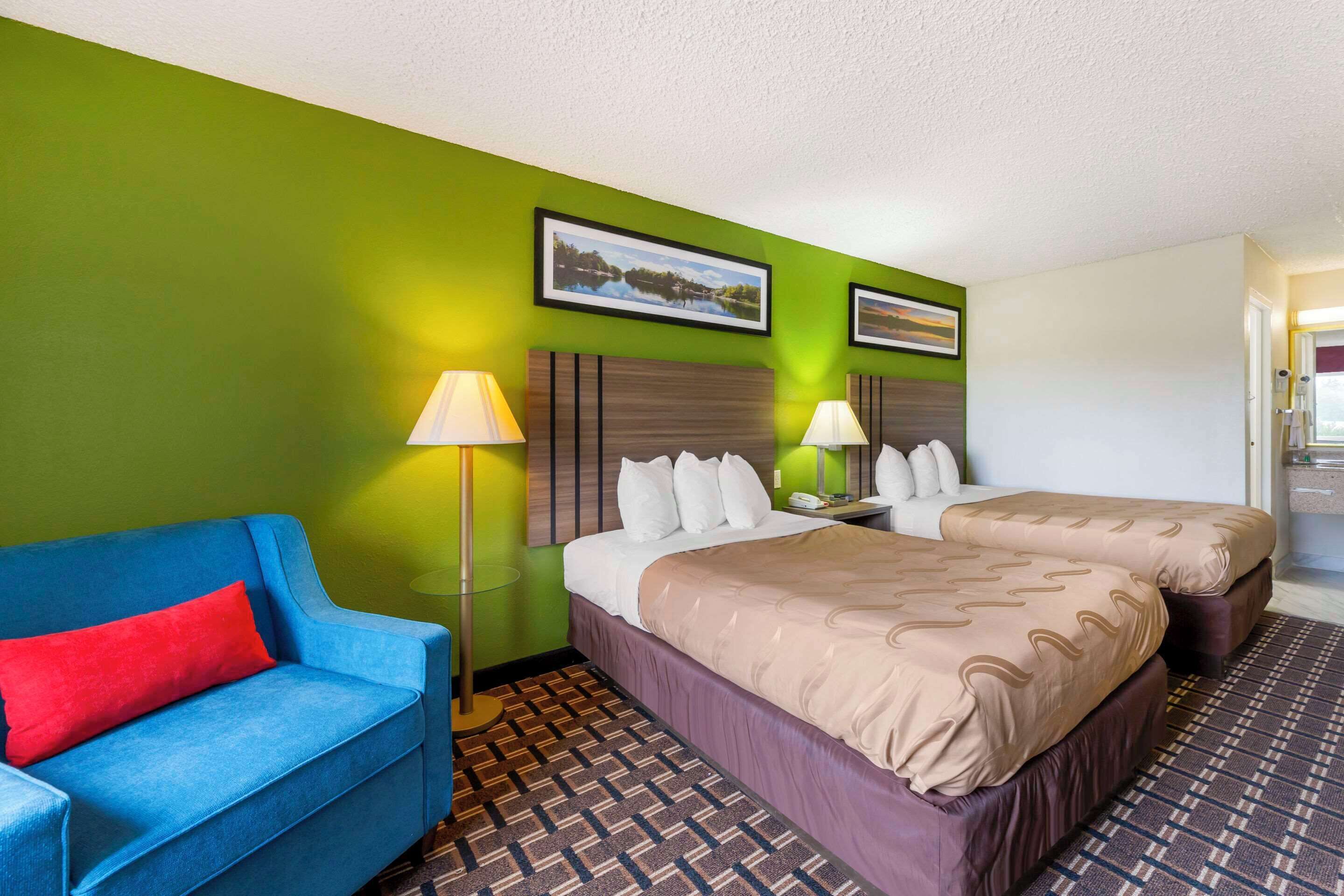 Habitación de hotel con dos camas, un sofá azul y una pared verde.
