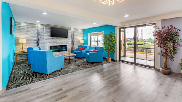 Un vestíbulo moderno con sofás azules, una televisión de pantalla plana, chimenea y ventanas amplias.