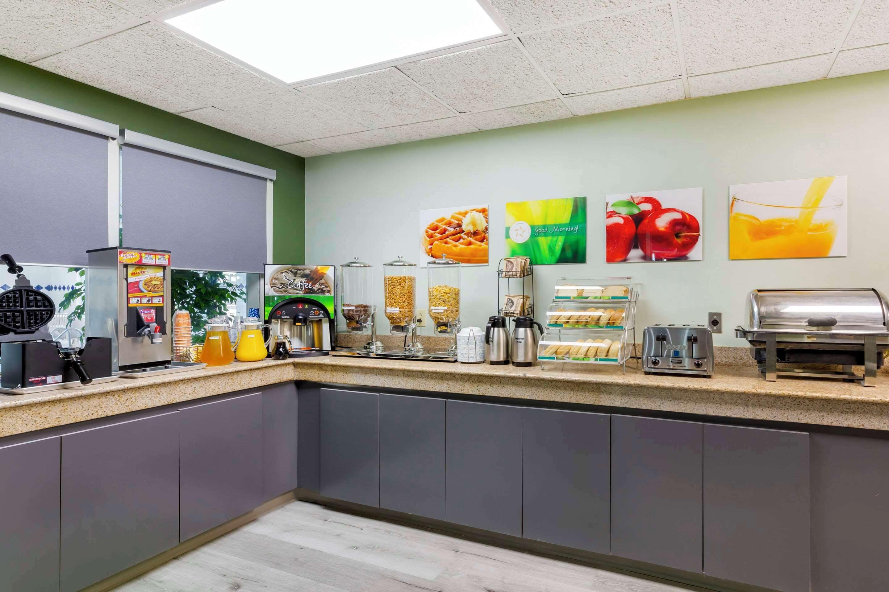 A breakfast bar with various food and drink dispensers, a waffle maker, and a coffee machine.