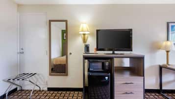 Una habitación de hotel compacta con kitchenette, televisor de pantalla plana, refrigerador pequeño y un espejo.