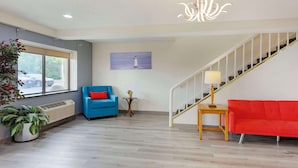 Un amplio salón con un sofá azul, un sofá rojo, una escalera y un cuadro de un faro.