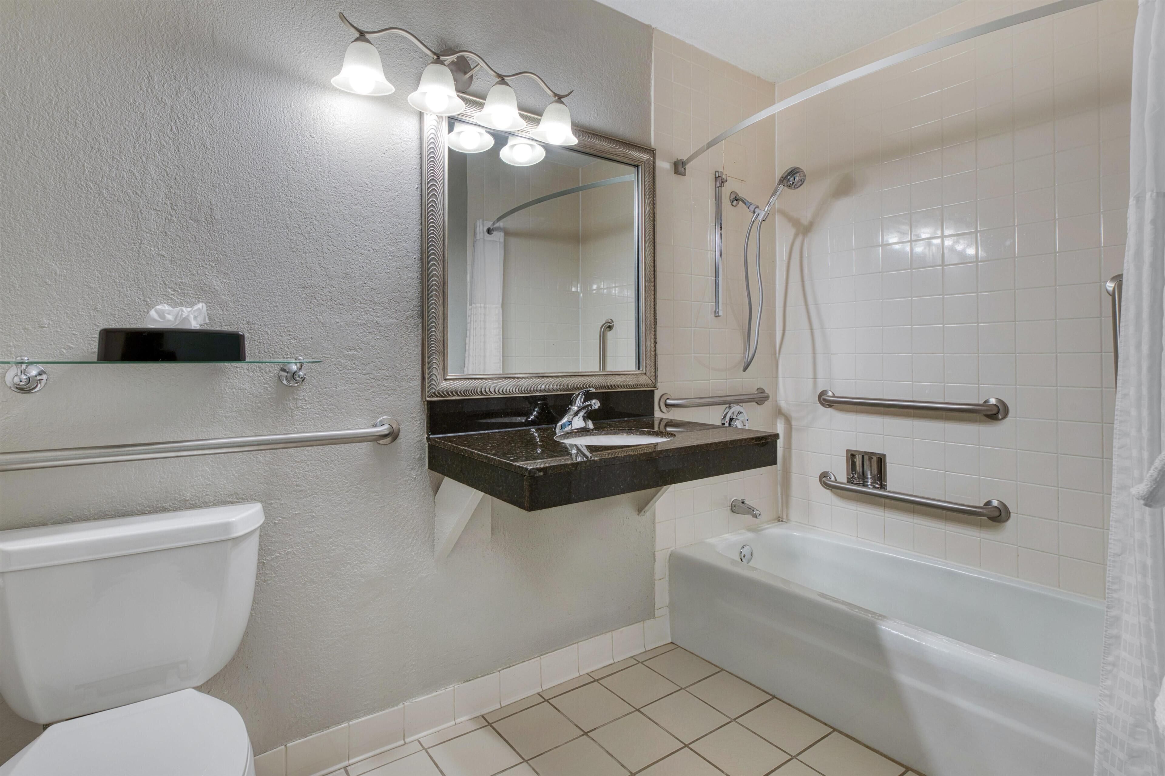 A bathroom with a toilet, sink, mirror, and bathtub.
