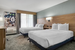 A hotel room with two beds, a desk, a chair, a large window with curtains, and a wall with a poster. - Best Western Tomah Hotel (Tomah)