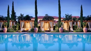 A poolside area with multiple cabanas, a clear pool, and tall cypress trees. - Rancho Bernardo Inn (San Diego)