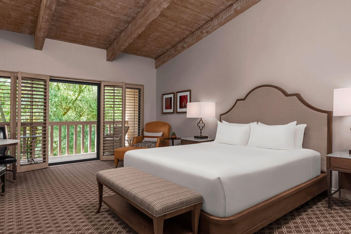 A spacious bedroom with a large bed, a wooden bench, a desk, and a chair.