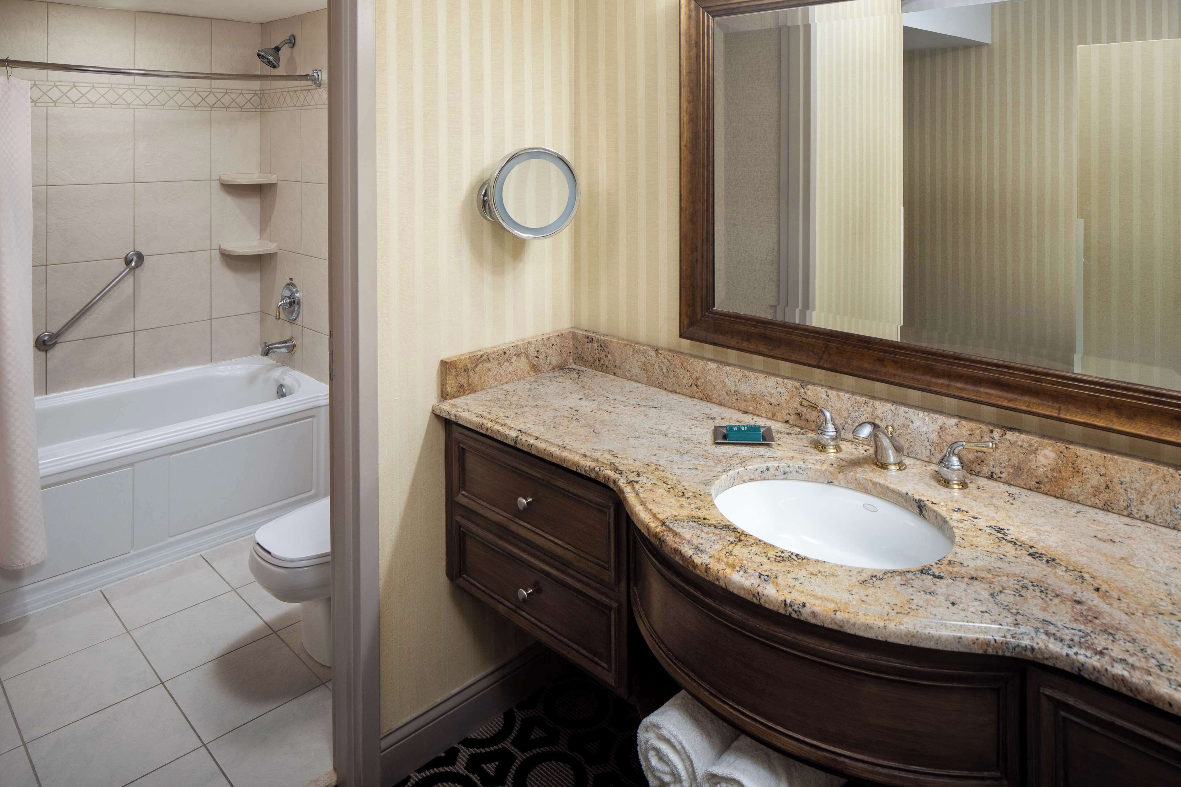 A bathroom with a bathtub, toilet, sink, vanity, and a mirror.