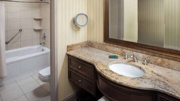 A bathroom with a bathtub, toilet, sink, vanity, and a mirror.