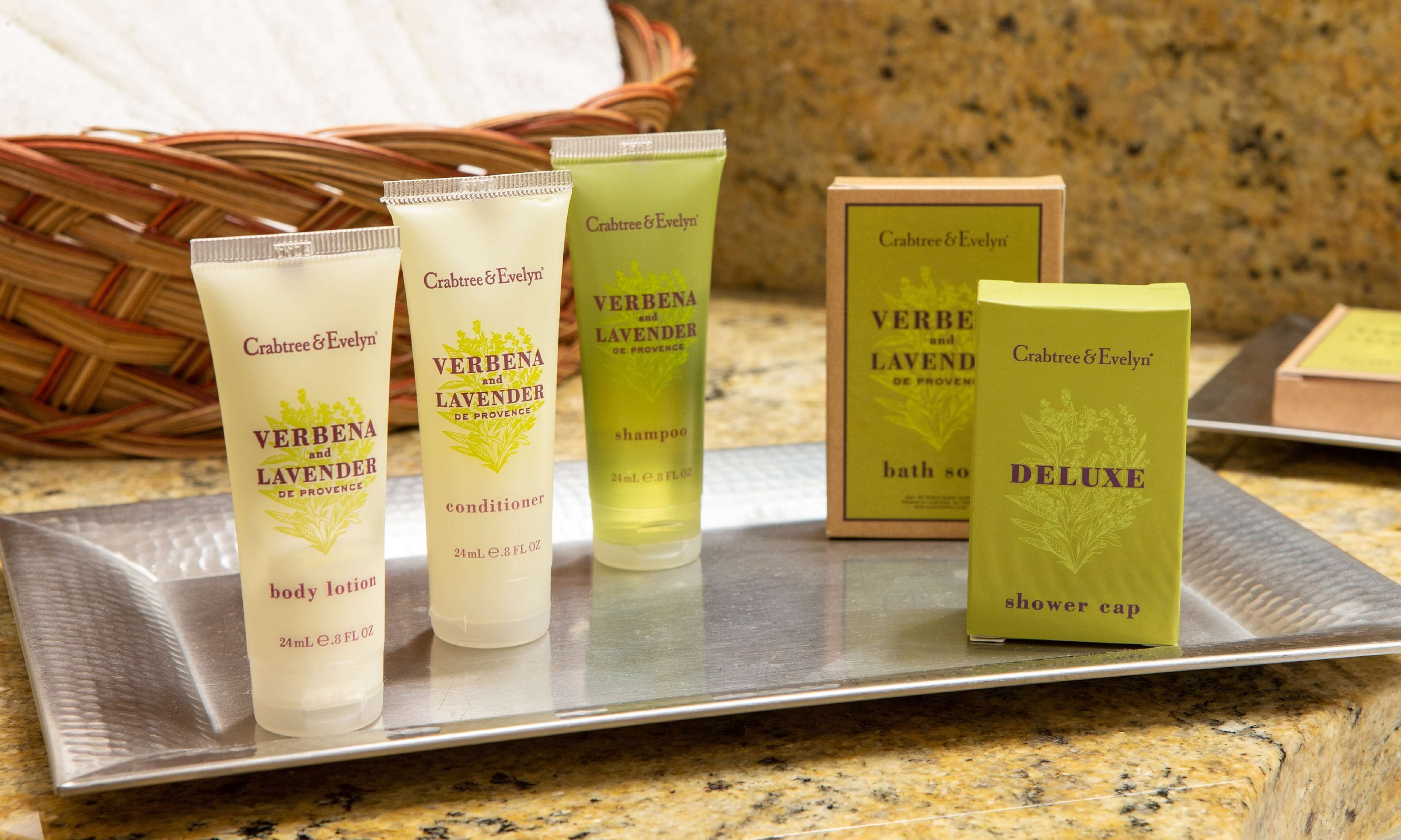 Una bandeja con varios productos Crabtree & Evelyn, entre ellos, loción corporal, acondicionador, champú, jabón de baño y un gorro de ducha.