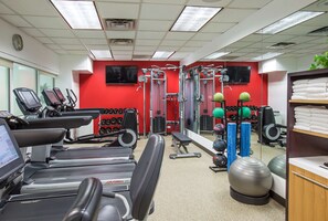Ein Fitnessstudio mit Laufbändern, Kraftgeräten und Übungsbällen.