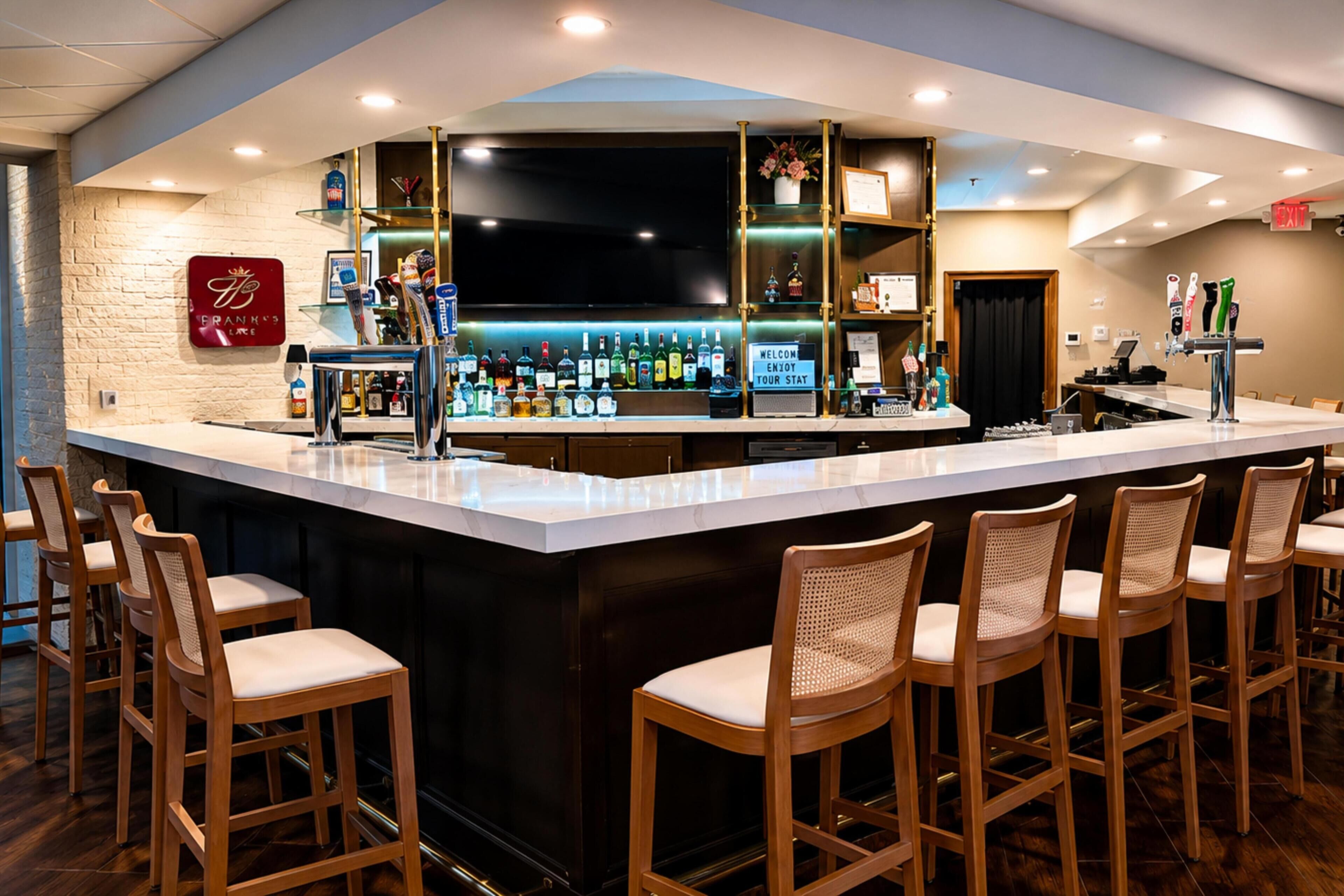 A bar area with a counter, stools, and a variety of bottles.