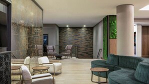 A modern lounge area with a sectional sofa, armchairs, and a small coffee table. - Courtyard by Marriott Chicago Downtown River North (Chicago)