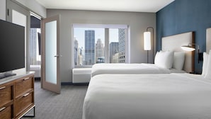 A hotel room with two beds, a TV, a dresser, and a large window with a city view. - Courtyard by Marriott Chicago Downtown River North (Chicago)