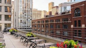 A rooftop terrace with outdoor seating and potted plants, surrounded by modern buildings. - Courtyard by Marriott Chicago Downtown River North (Chicago)