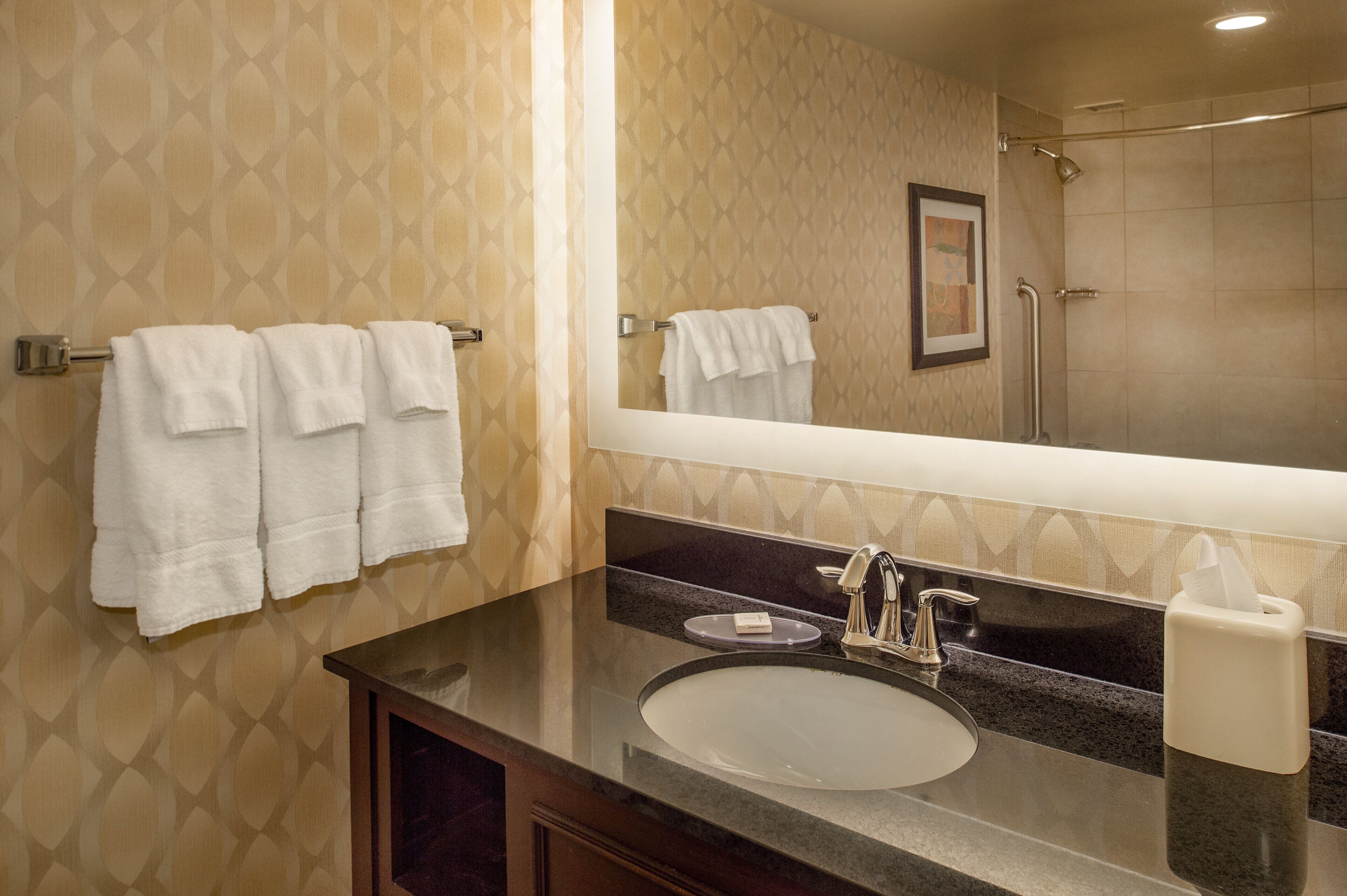 A bathroom with a sink, mirror, and towels on a rack.