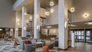 A spacious lobby with high ceilings, multiple seating areas, and modern pendant lighting.