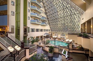 A multi-level hotel lobby with a central pool, multiple balconies, and a distinctive geometric glass ceiling.