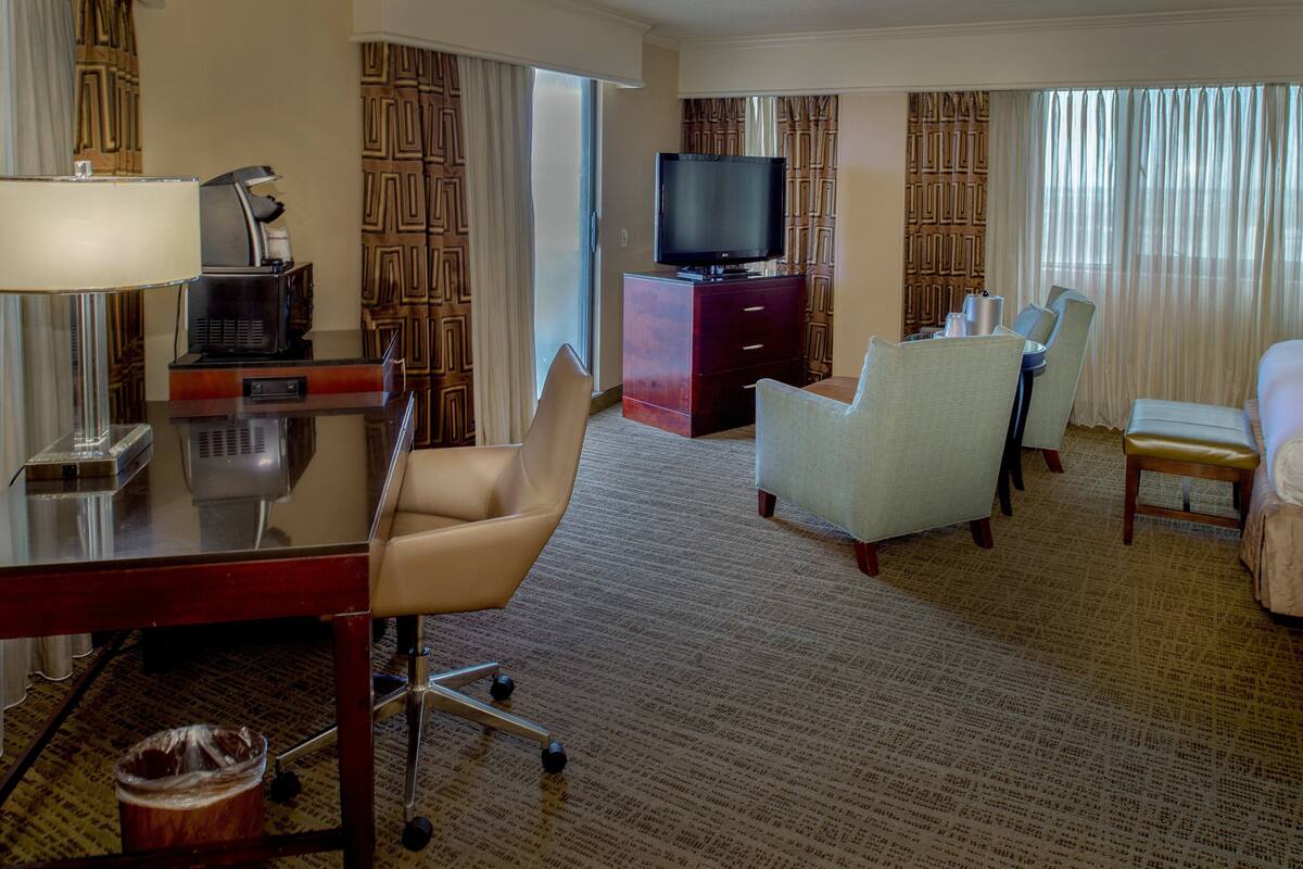 Une chambre d’hôtel équipée d’un bureau, de chaises, d’une télévision et d’un lit.