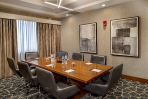 A conference room with a long table, six chairs, water bottles, and two abstract paintings on the walls. - Crowne Plaza St. Louis Airport by IHG (Bridgeton)