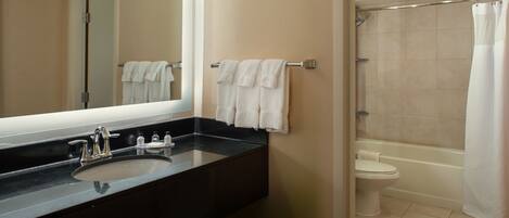 A bathroom with a black sink, a mirror, a toilet, and a shower.