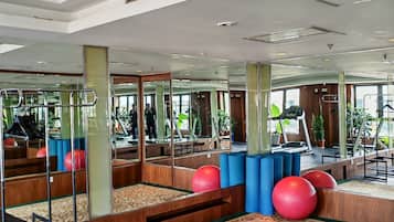 Un gimnasio con equipo de ejercicio, espejos y una alfombra estampada.