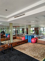 A gym with exercise equipment, mirrors, and a patterned carpet.