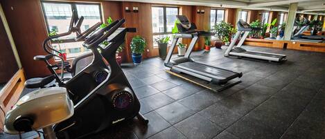 Un gimnasio con bicicletas estáticas, cintas de correr y equipo de ejercicio.