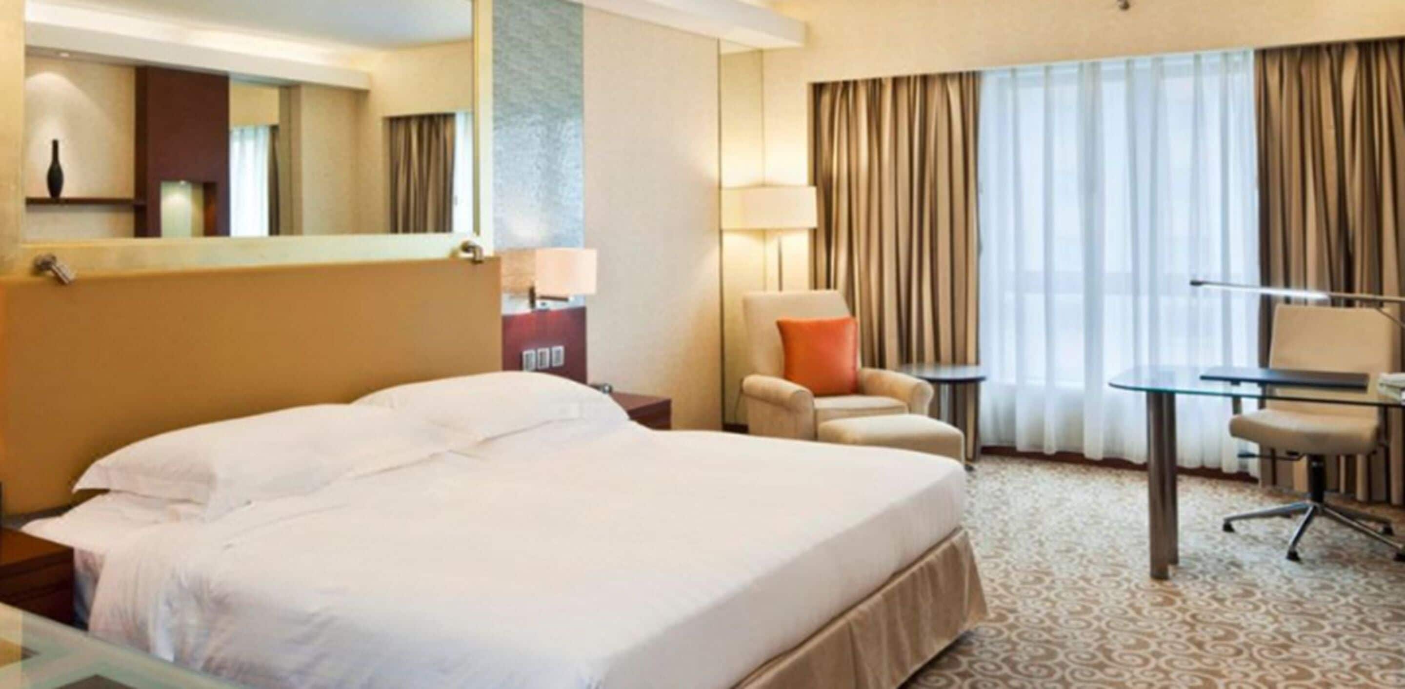 Una habitación de hotel con una cama grande, dos sillones, una mesita y un escritorio.