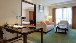 Habitación de hotel con escritorio, silla, sofá y un espejo grande.