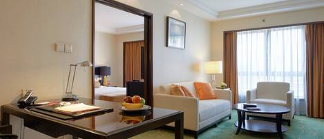 A hotel room with a desk, a chair, a sofa, and a large mirror.