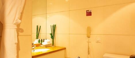 A bathroom with a toilet, sink, mirror, and a robe hanging on the wall.