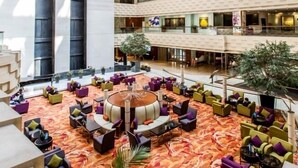 Un vestíbulo amplio con techo alto, varios pisos y una zona de estar central con mobiliario colorido.
