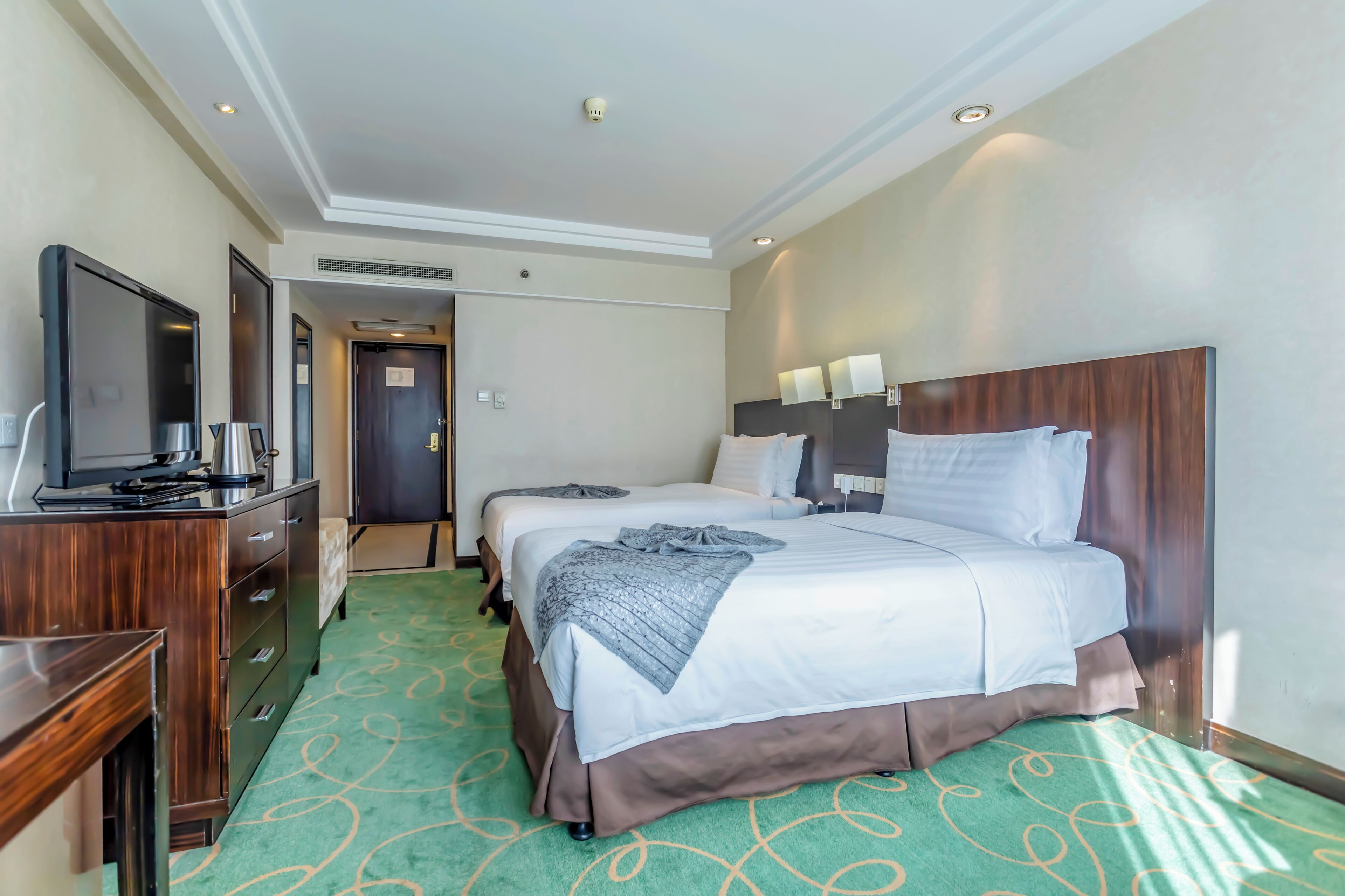 Una habitación de hotel con una cama grande, un escritorio con televisor y un armario.