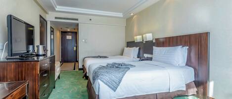 Una habitación de hotel con una cama grande, un escritorio con televisor y un armario.