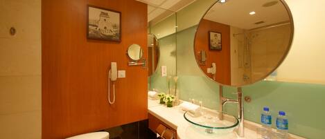 A modern bathroom with a toilet, a glass sink, a large mirror, and a shower.
