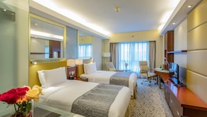 Habitación de hotel con dos camas, un escritorio, un televisor y un espejo grande.
