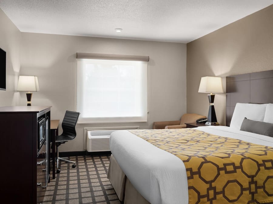 A hotel room with a bed, desk, chair, and a television on the wall.