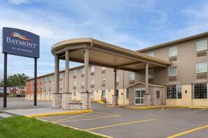Un hotel Baymont con entrada cubierta, varios pisos y estacionamiento.