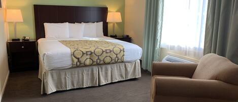 A hotel room with a large bed, two bedside lamps, a chair, and a window with curtains.