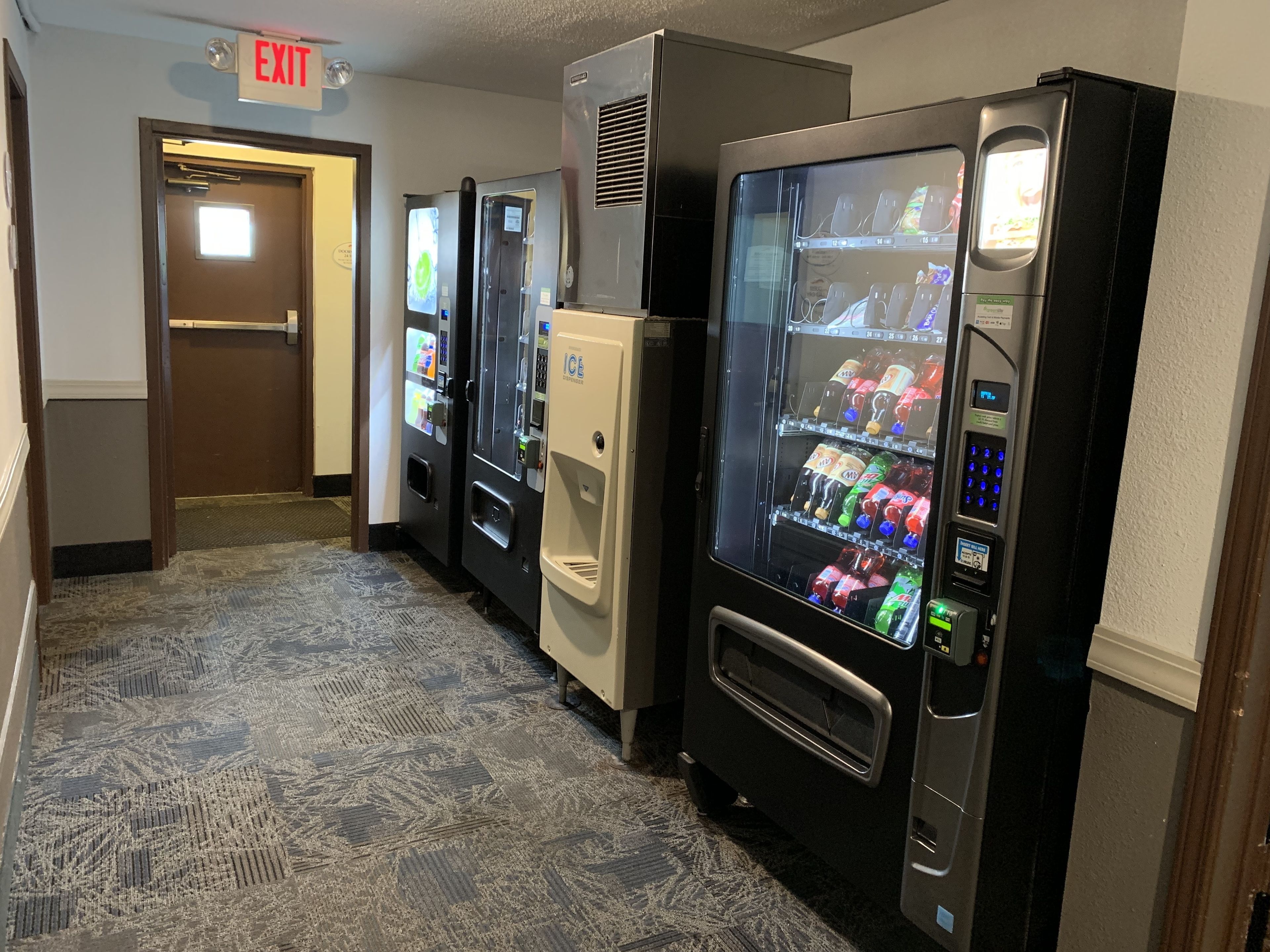 A hallway with vending machines and an exit sign.