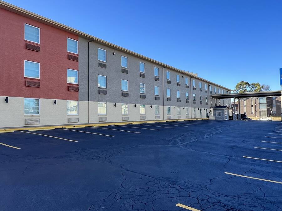 Ett hotell med flera våningar och en parkeringsplats framför.