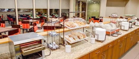 A breakfast buffet with various food items, a coffee station, and seating areas.