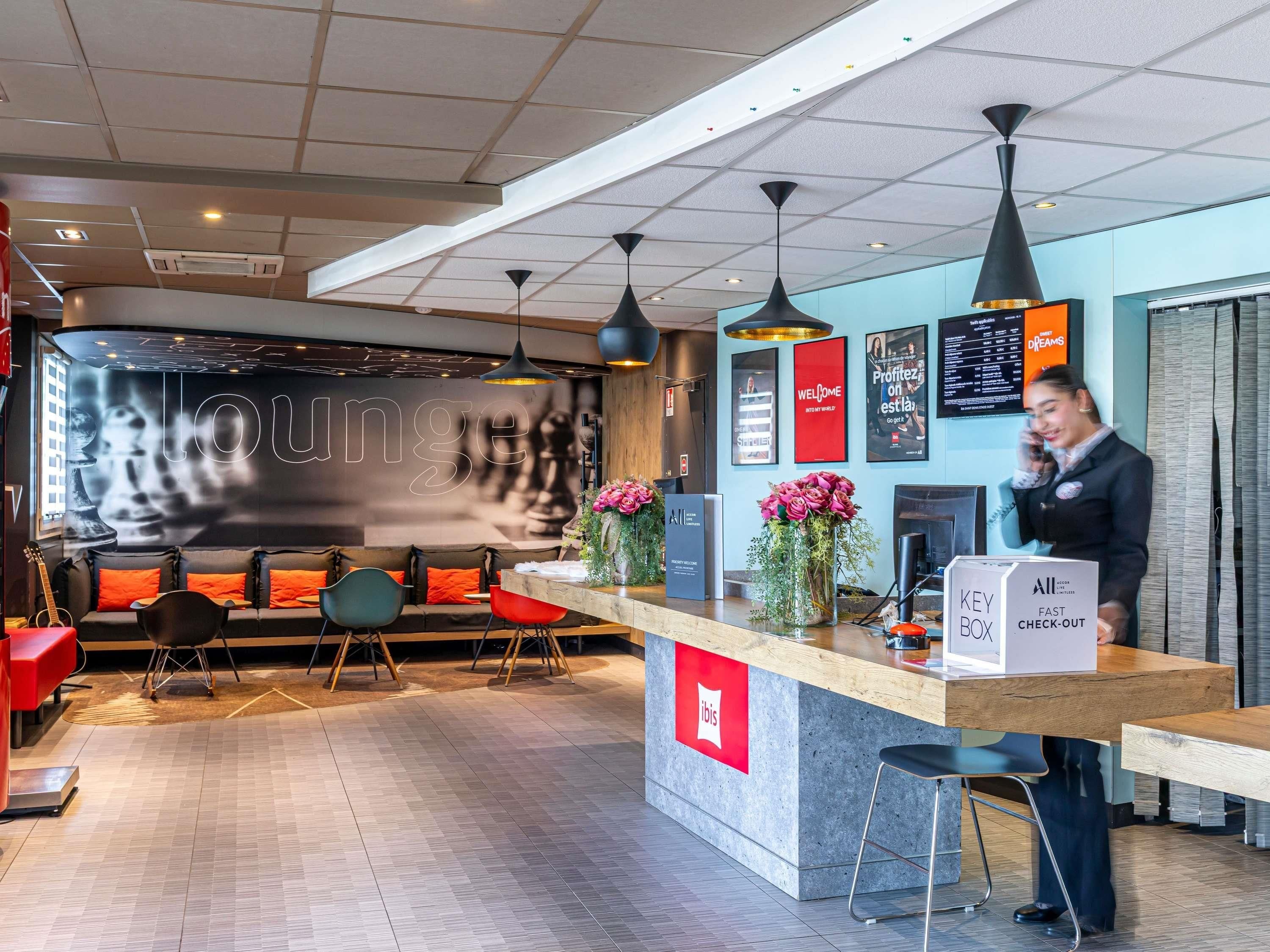 A modern hotel lobby with a reception desk, seating area, and a large wall with a 'loung' sign.