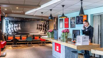 A modern hotel lobby with a reception desk, seating area, and a large wall with a 'loung' sign.