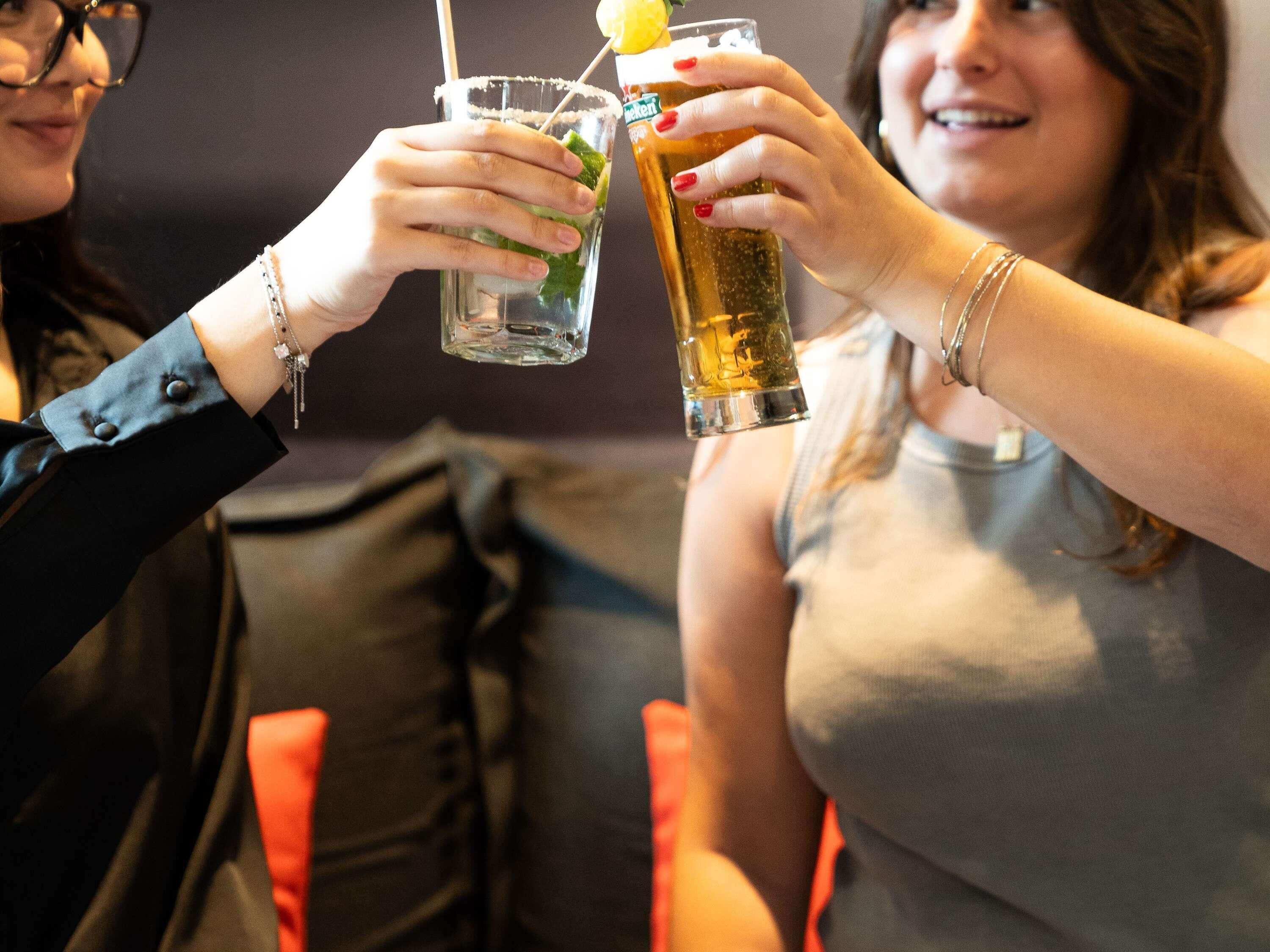 Two people toasting with drinks in a casual setting.