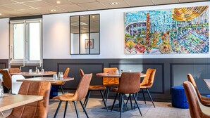 Un comedor moderno con un gran mural, mesas de madera y sillas tapizadas en tonos marrones.