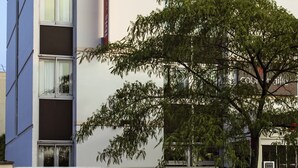 Un moderno edificio de hotel con un llamativo letrero de 'ibis HOTEL' en el techo.