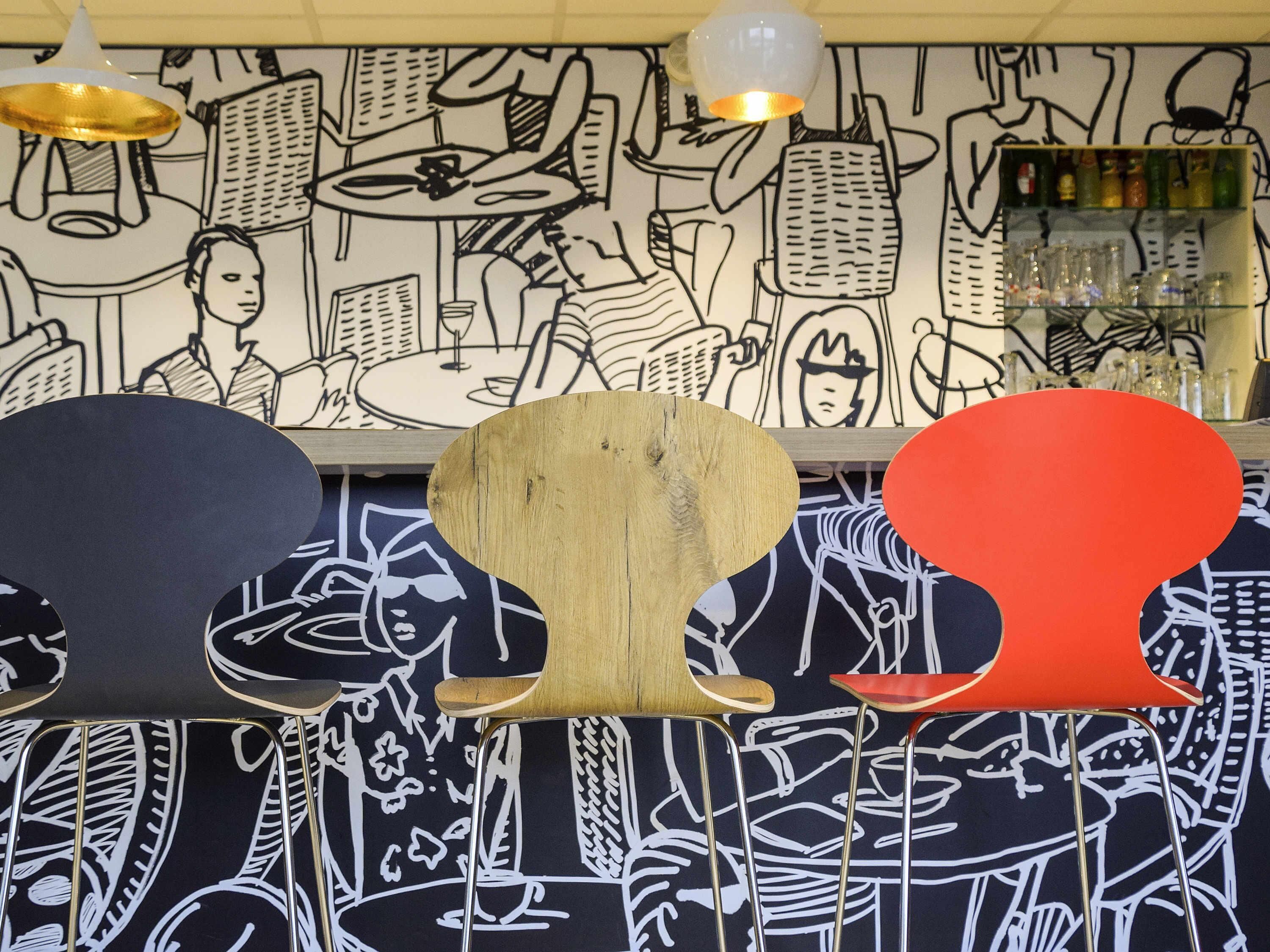 A bar area with a unique wall art design, a wooden bar counter, and a red accent piece.